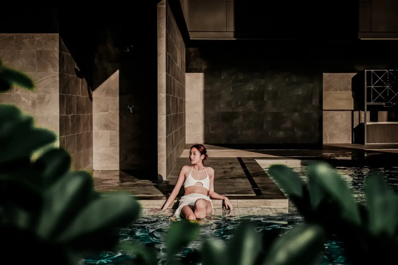 woman in a white bikini relaxes by the poolside at Ascott Thonglor Bangkok