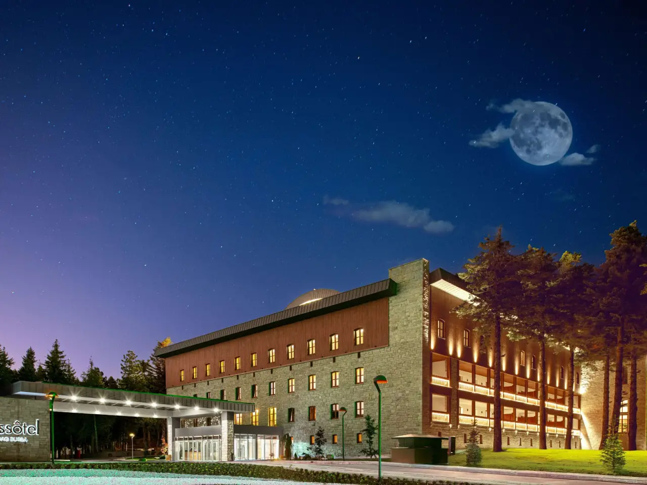 Gece vakti aydınlatılmış Swissôtel Uludağ Bursa otel binası, yıldızlı bir gökyüzü ve dolunay manzarası ile.