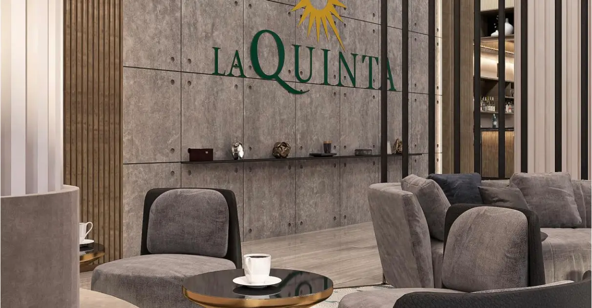 Interior of La Quinta by Wyndham, featuring modern seating and a stylish wall design with the brand logo.