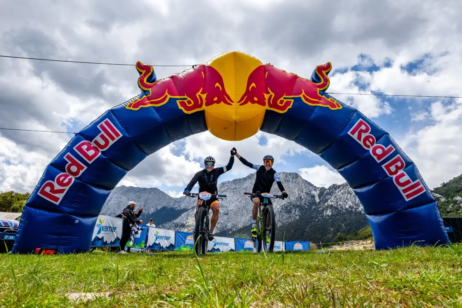 Trans Taurus Dağ Bisikleti Etap Yarışları’nda Red Bull kemeri altında bitiş çizgisini geçen iki bisikletçi.
