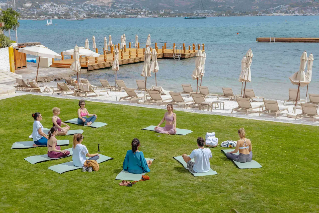 Avantgarde Refined Yalıkavak otelinin sahil çim alanında yoga yapan misafirler
