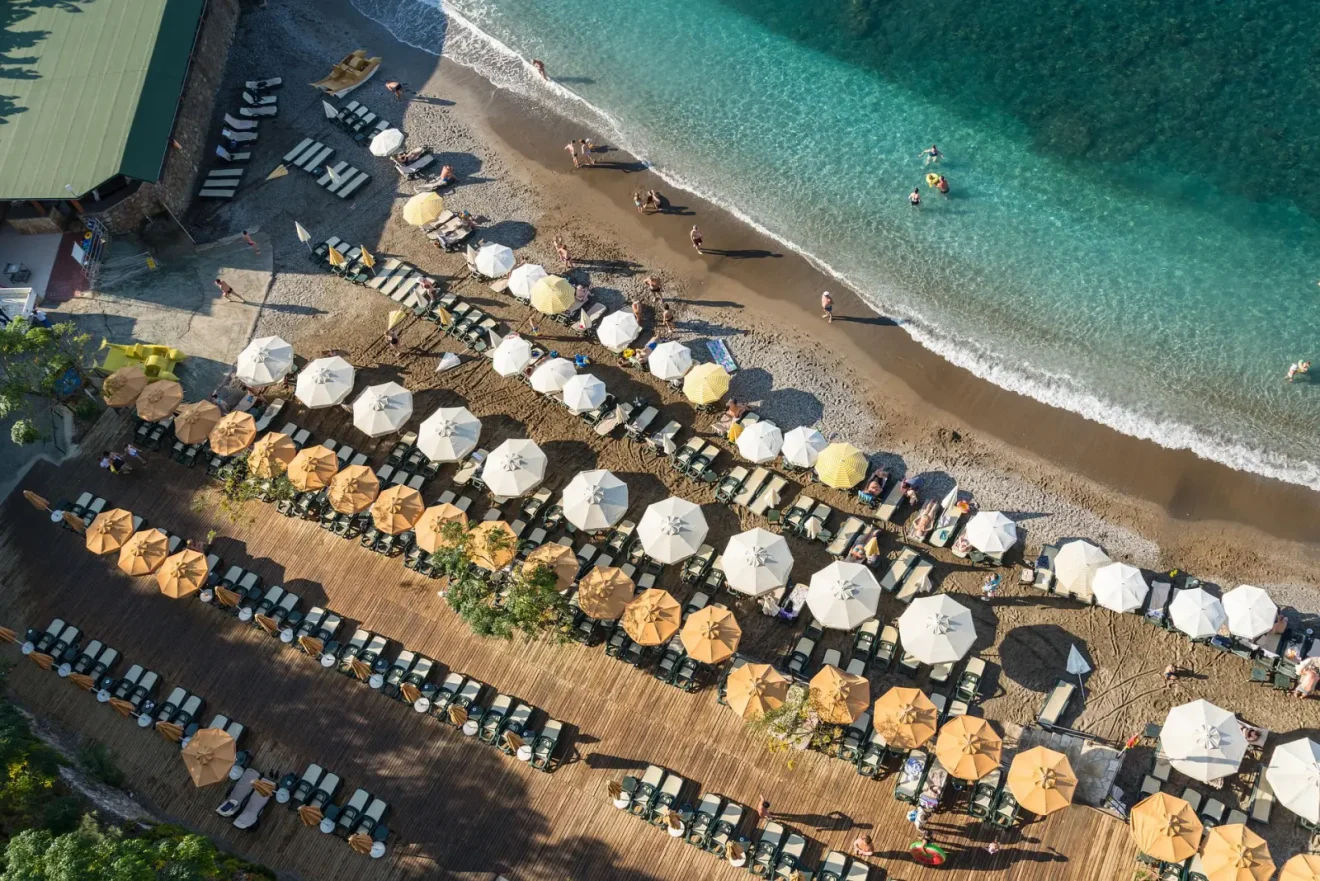 Alanya’da deniz kenarında sıralanmış şezlonglar ve renkli şemsiyeler