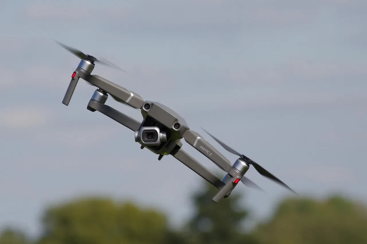 Gündüz açık havada uçan yarış dronu, arka planda bulanık ağaçlarla