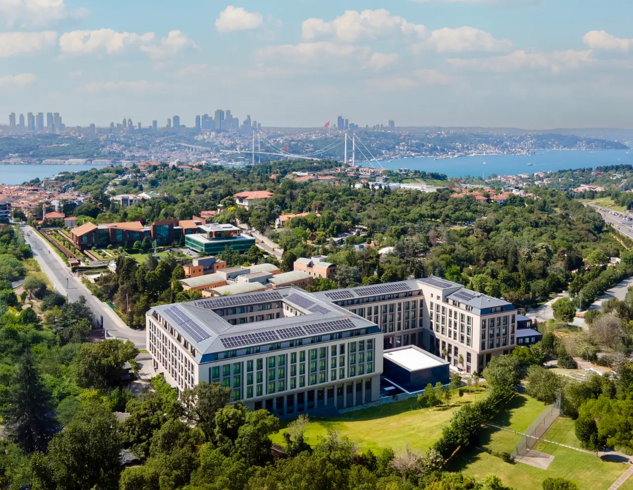 Altunizade Suites İstanbul otelinin Boğaz manzaralı havadan görünümü, arka planda Boğaziçi Köprüsü ve Avrupa Yakası silueti.