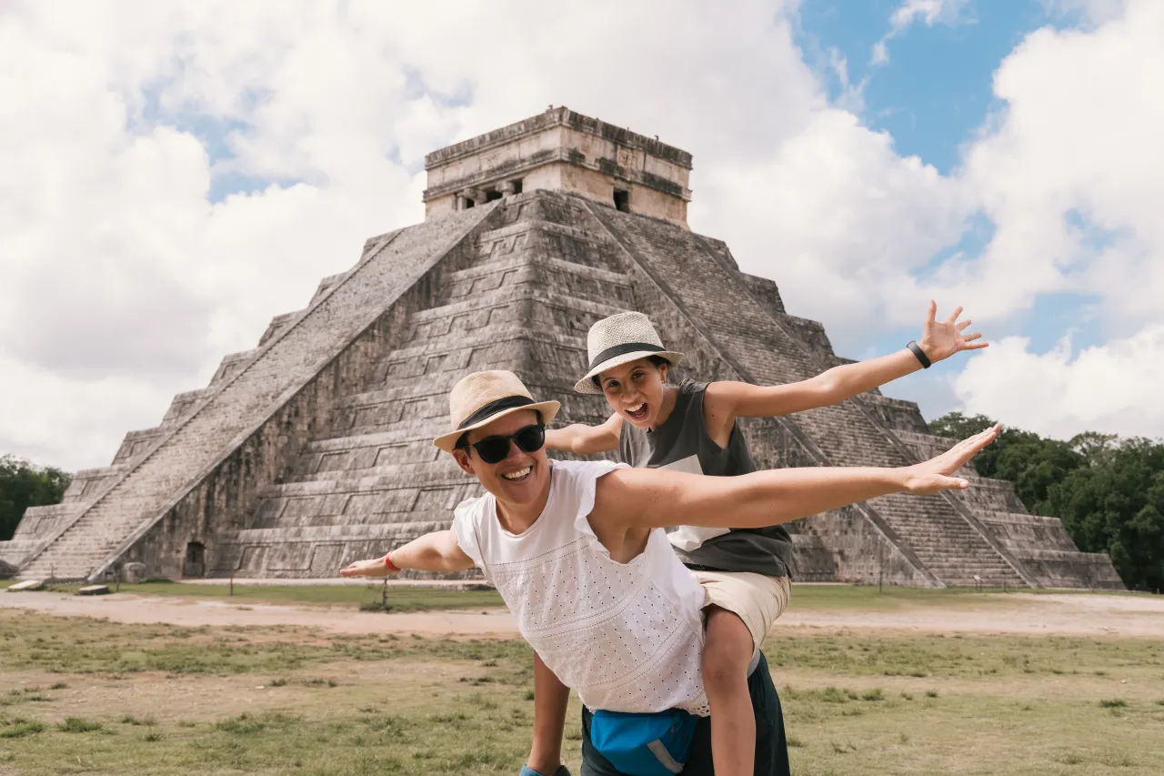 Chichen Itza piramidi önünde poz veren eğlenceli turist anne ve kızı, Meksika