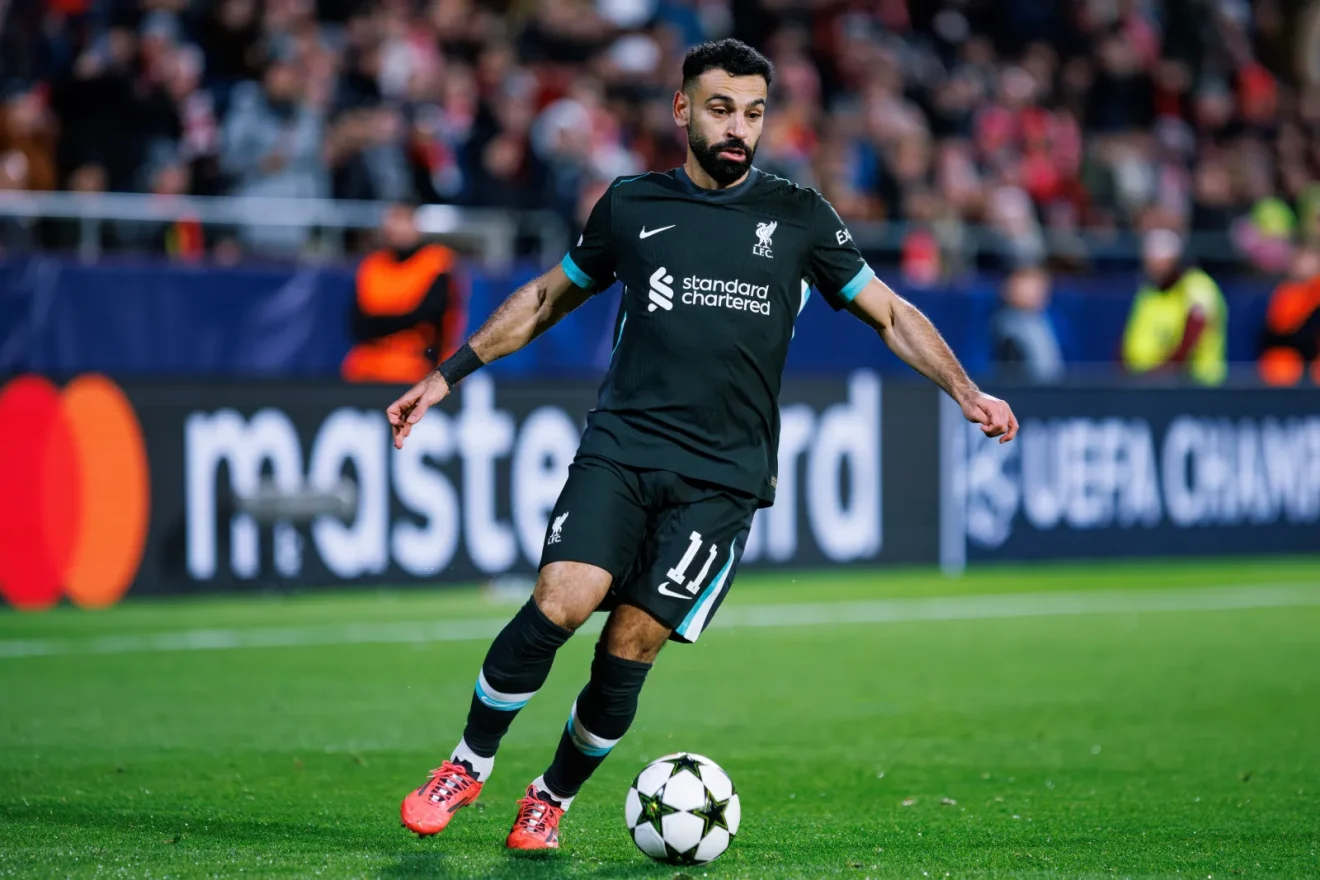 Liverpool formasıyla Mohamed Salah, UEFA Şampiyonlar Ligi maçında top sürerken sahada odaklanmış şekilde görülüyor.