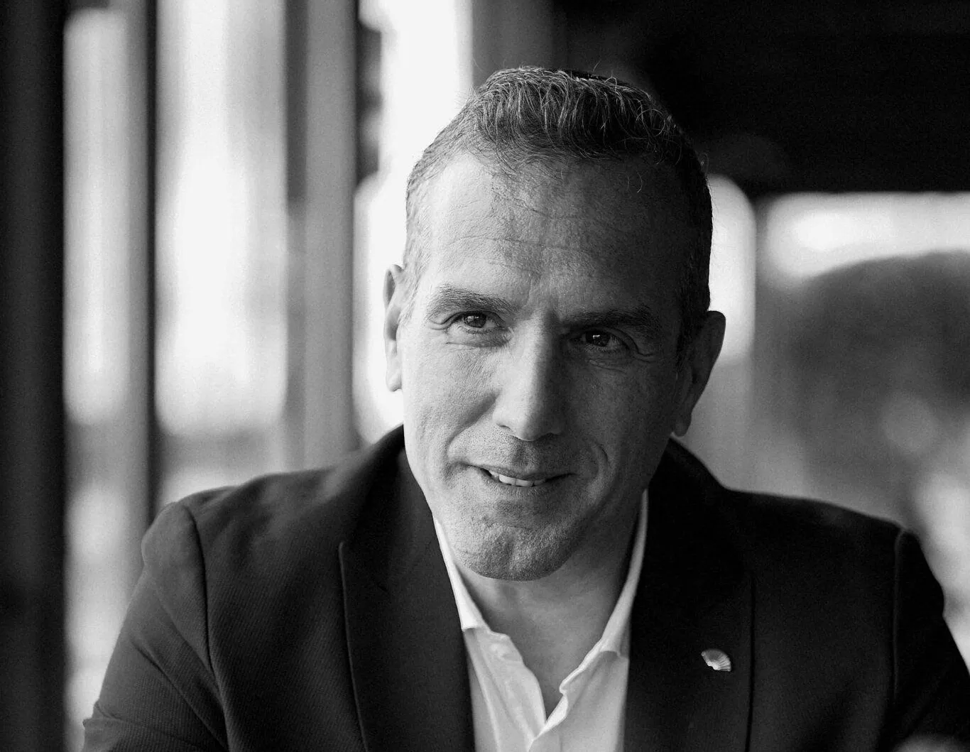 Takım elbiseli Tunç Batum pencere kenarında oturuyor, siyah beyaz portre