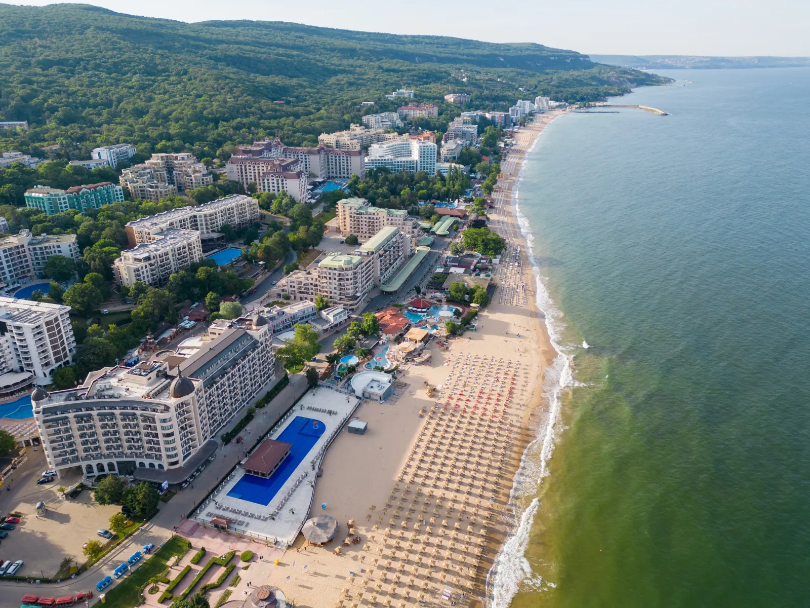 Varna Bulgaristan sahil şeridi, oteller, plaj şemsiyeleri ve Karadeniz kıyısındaki yeşil tepelerle ünlü bir turistik destinasyonu gösteriyor.