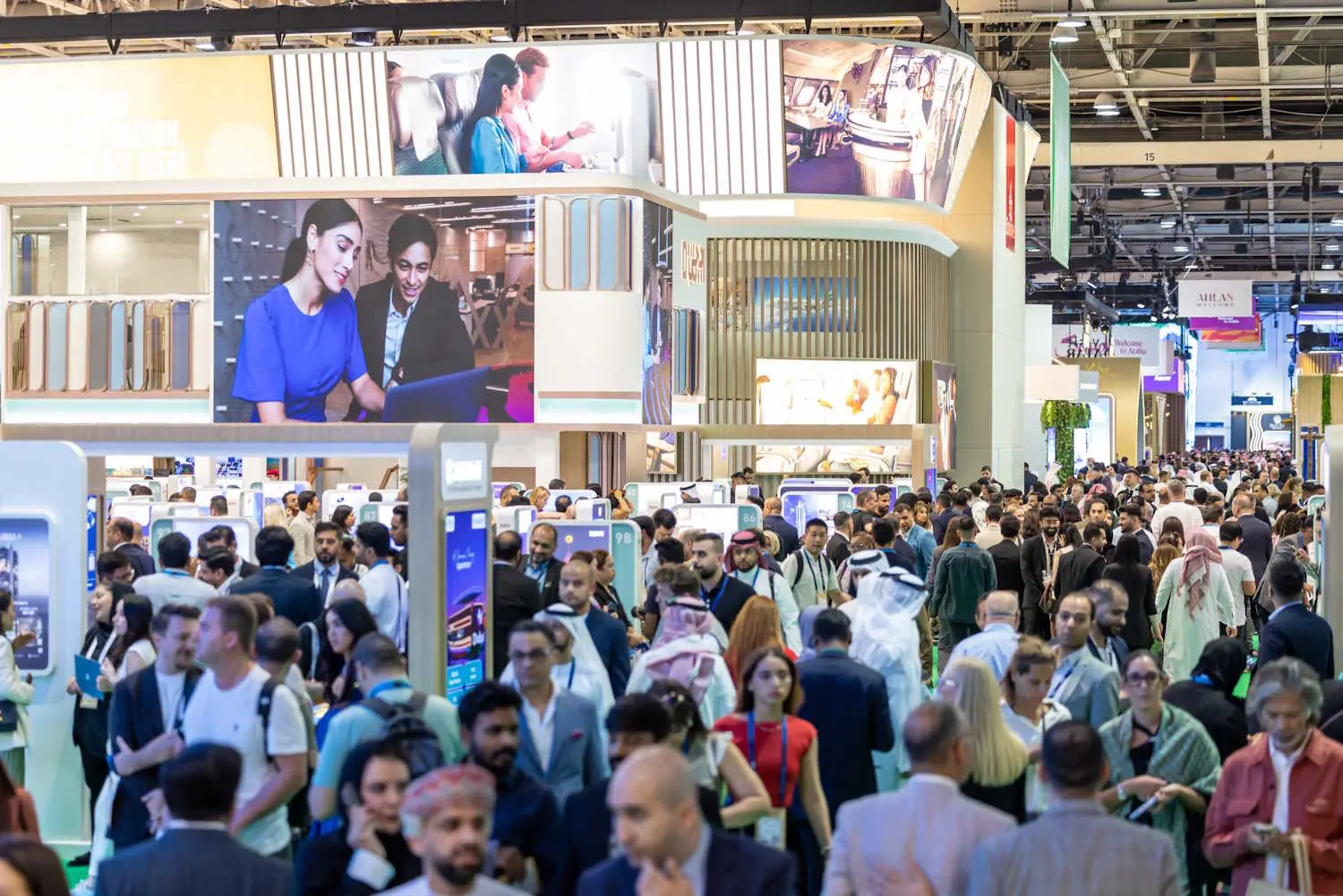 Visitors explore crowded exhibition halls at Arabian Travel Market in Dubai, showcasing global tourism brands.