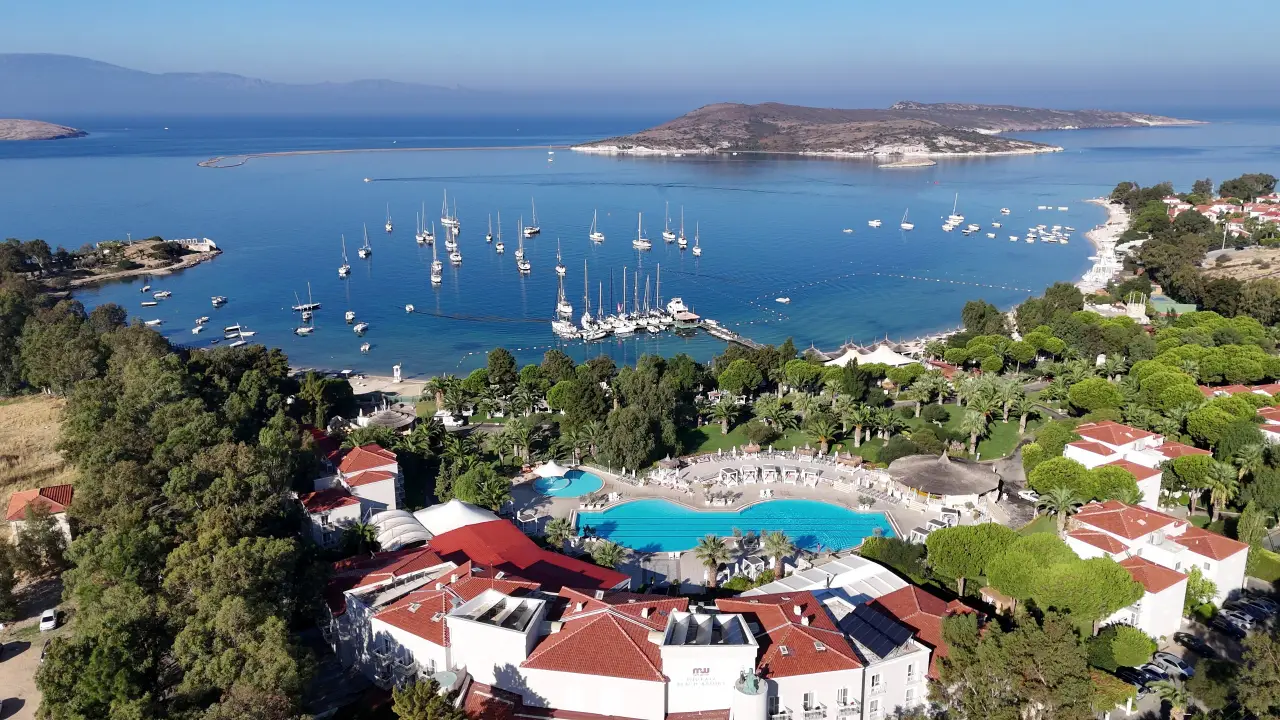 Türkiye’de denize kıyısı olan bir tatil tesisinin havuzları, yemyeşil alanları ve koyda demirlemiş yatlarla görülen havadan çekilmiş manzara.