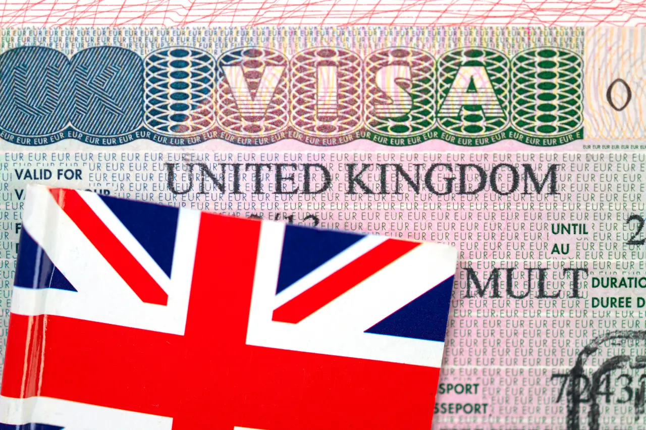 Birleşik Krallık bayrağı önünde, “Visa” ve “United Kingdom” yazıları görünen yakın plan İngiltere vizesi.