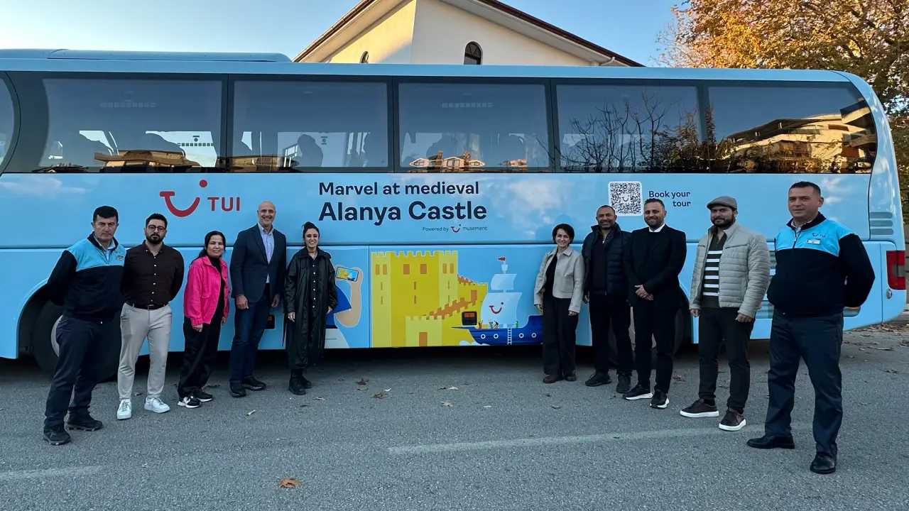 TUI operasyon aracı önünde Alanya Kalesi görselleriyle kaplanmış otobüs ve tanıtım ekibi toplu halde poz veriyor.