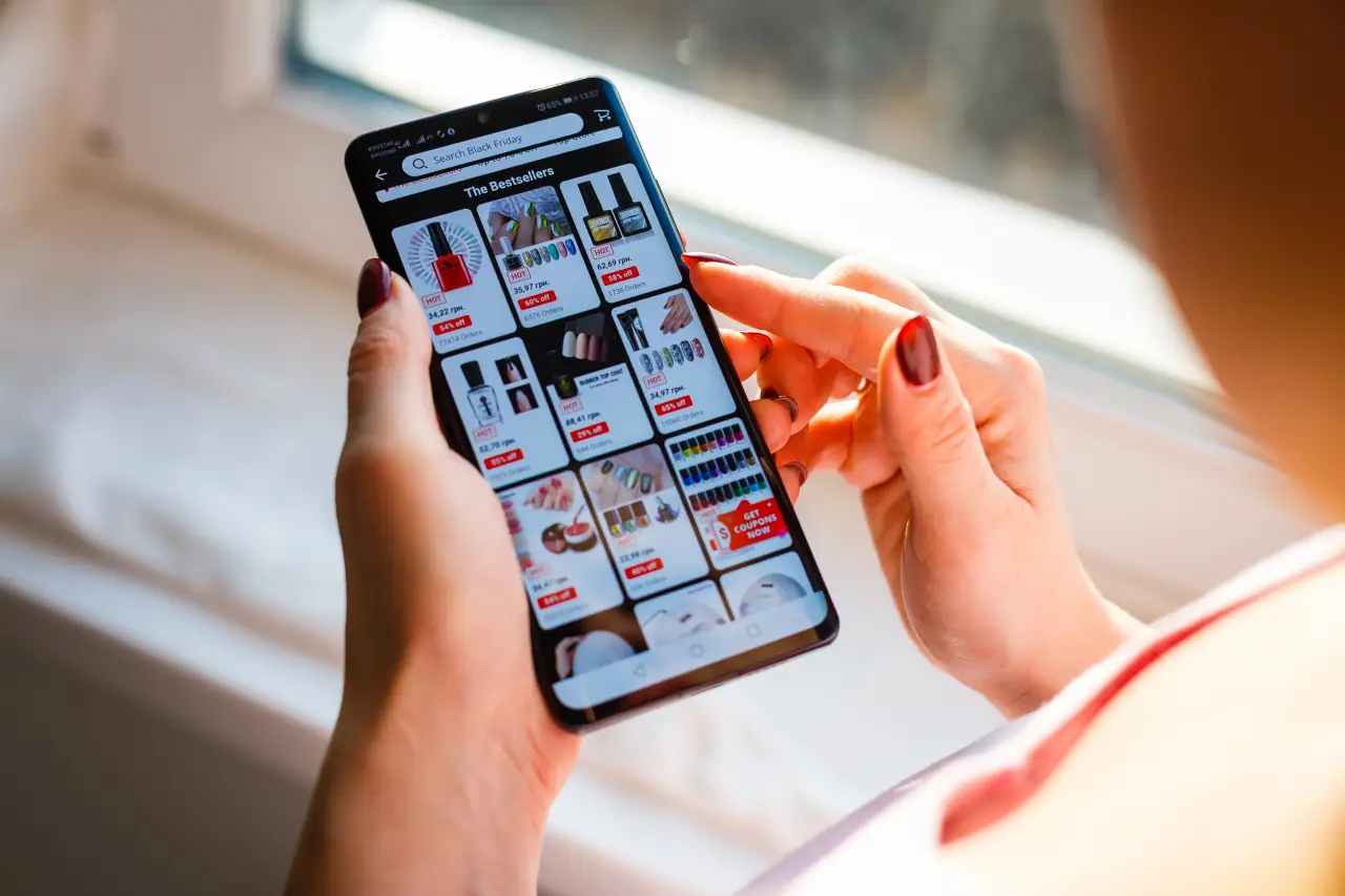Bir kişinin cep telefonundan online alışveriş uygulamasında ürünleri incelemesi