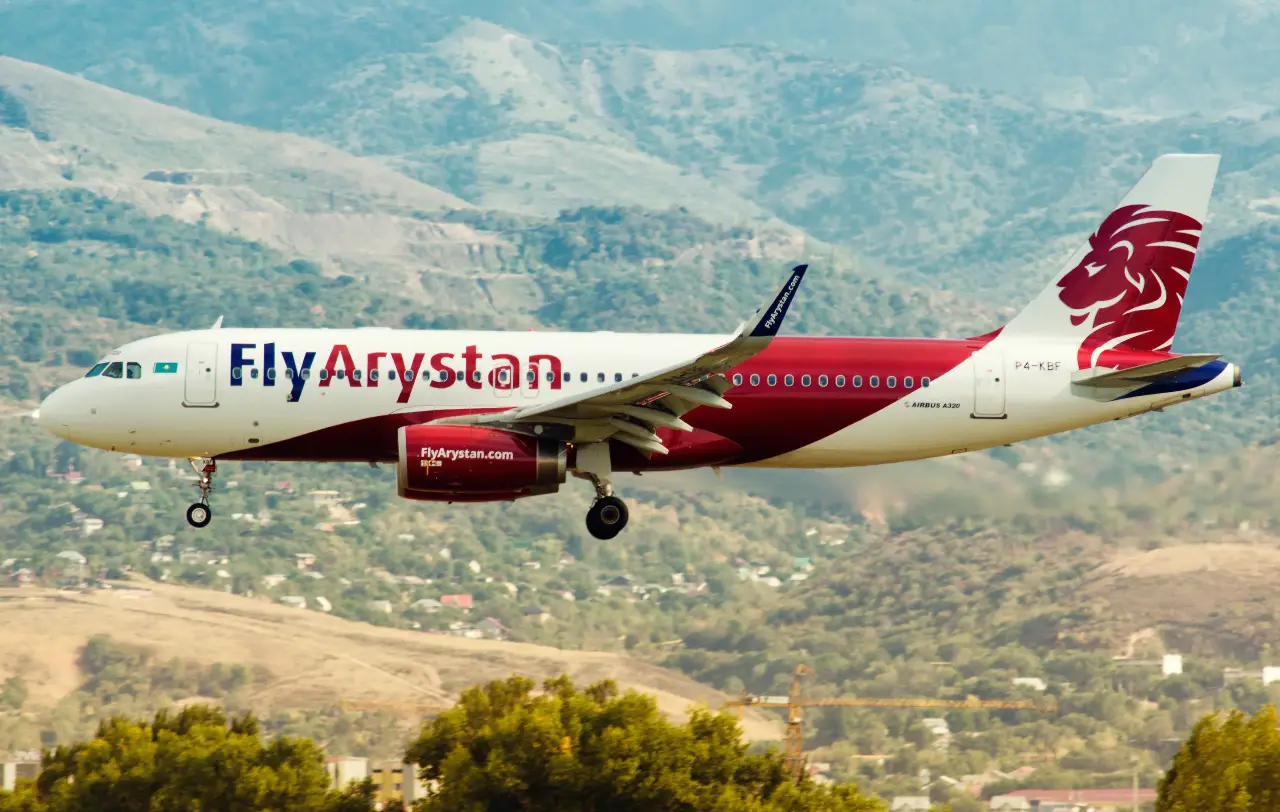 FlyArystan Airbus A320 passenger jet flying over mountainous landscape