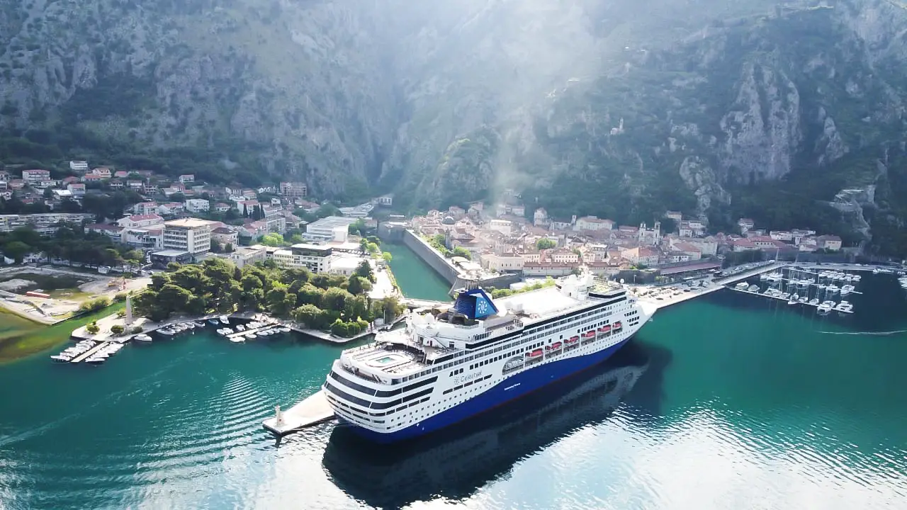 Karadağ Kotor Körfezi limanında dağlar arasında demirleyen büyük bir cruise gemisi