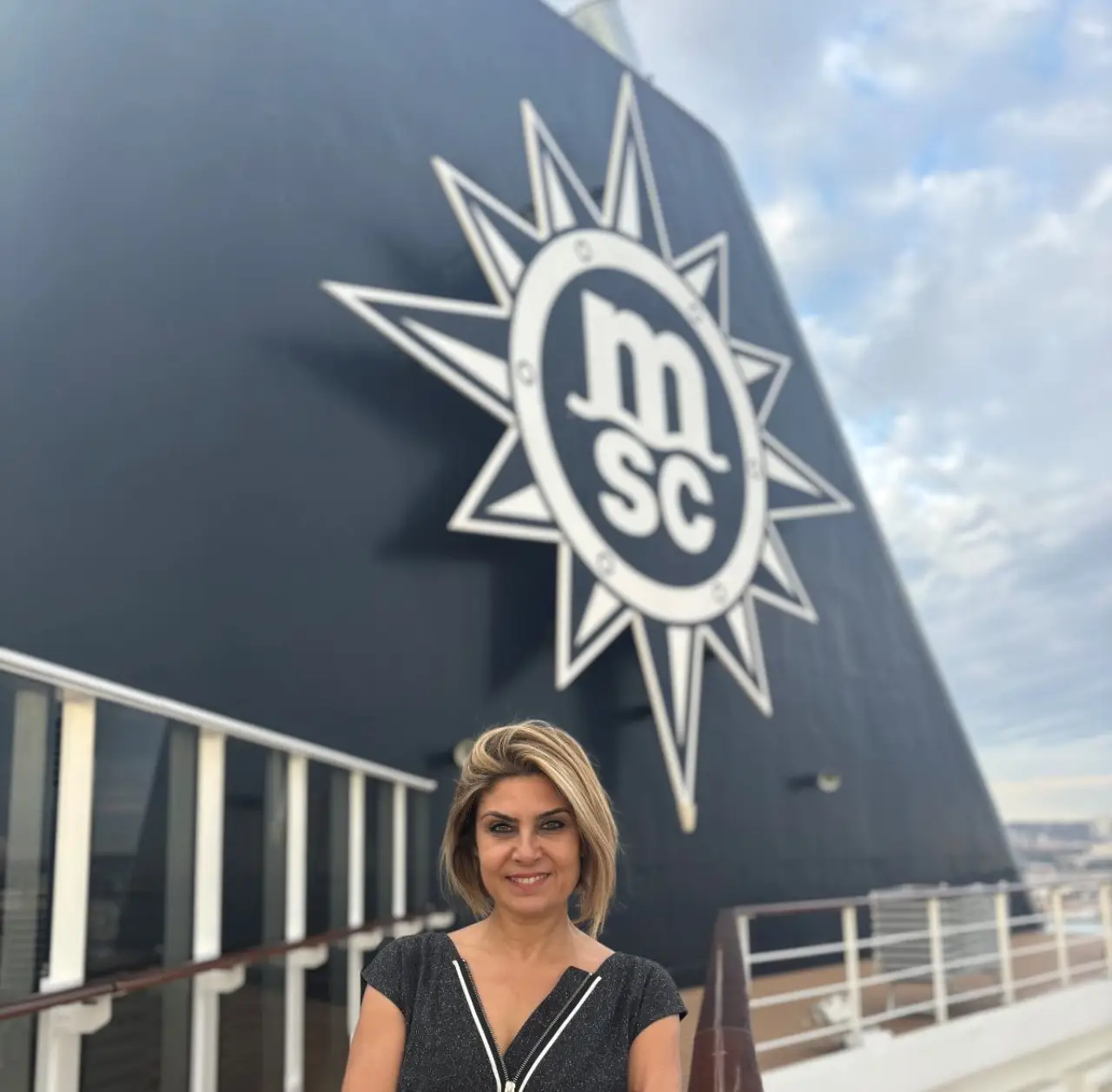 MSC Cruises gemisinde MSC logosu önünde poz veren MSC Cruises Türkiye ülke müdürü Işın Hekimoğlu