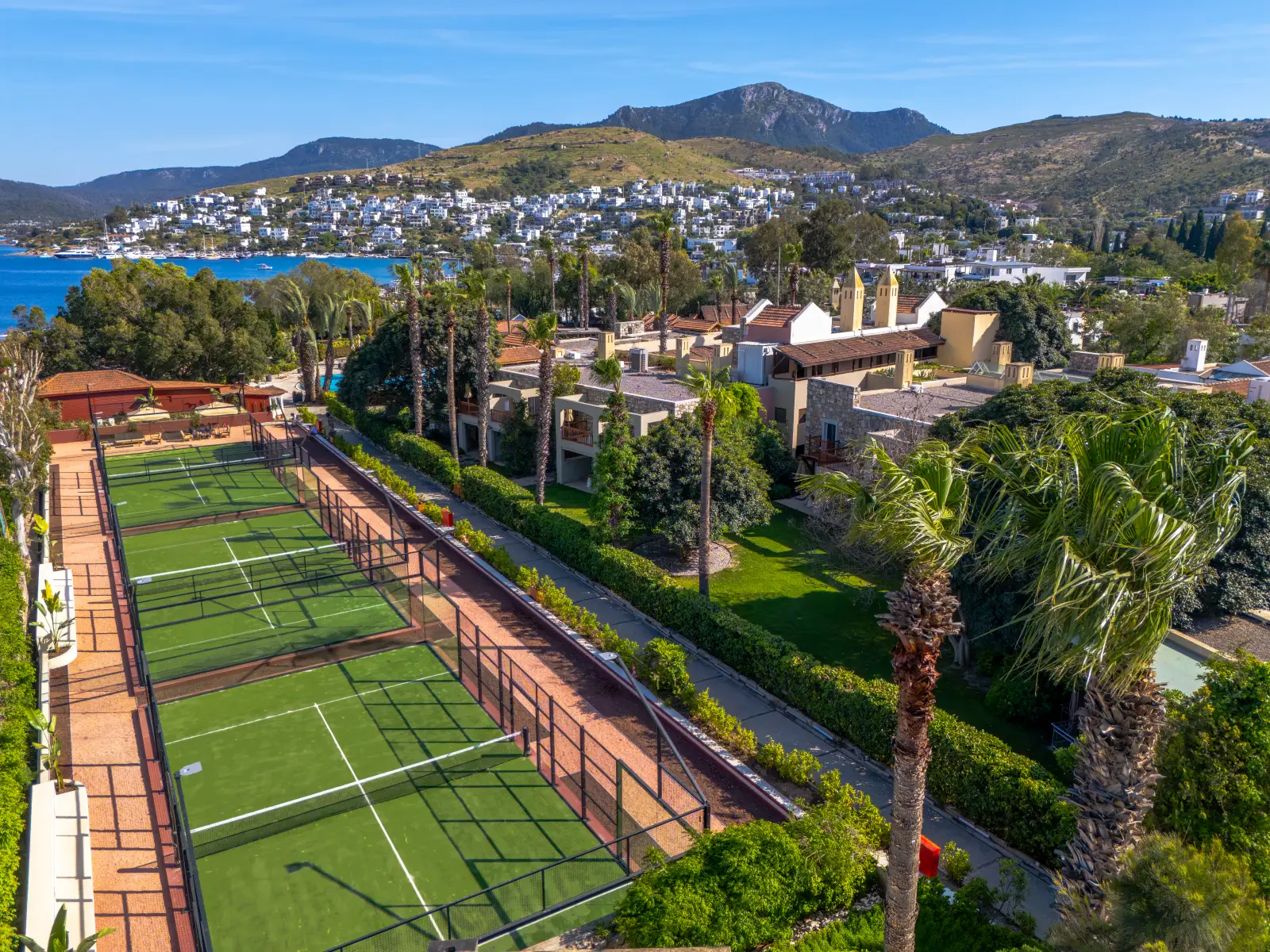 Divan Bodrum'daki Nano Padel Club kortları, arka planda Türkbükü koyuyla havadan görünüyor