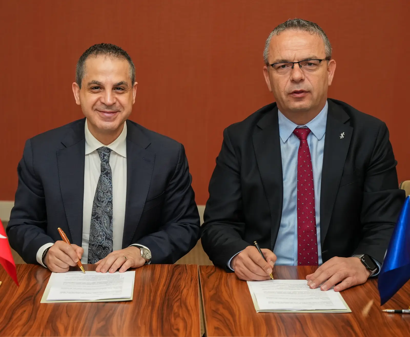 TÜROFED Başkanı Erkan Yağcı ve İş Bankası Genel Müdür Yardımcısı Sezgin Yılmaz, otel yatırımcılarına özel kredi paketi iş birliği protokolünü imzalarken yan yana oturmuş şekilde görülüyor. Arka planda Türk bayrağı ve İş Bankası bayrağı yer alıyor.